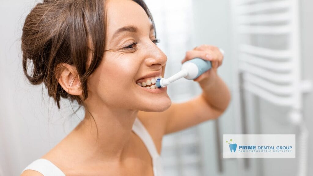 Woman brushing her teeth with an electric toothbrush, demonstrating proper technique